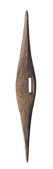 Thin wooden shield carved with the centre wider than to top and bottom ends. To the right is a rectangle cavity in the centre. The face of the shield features a line pattern of repeated diamonds. 