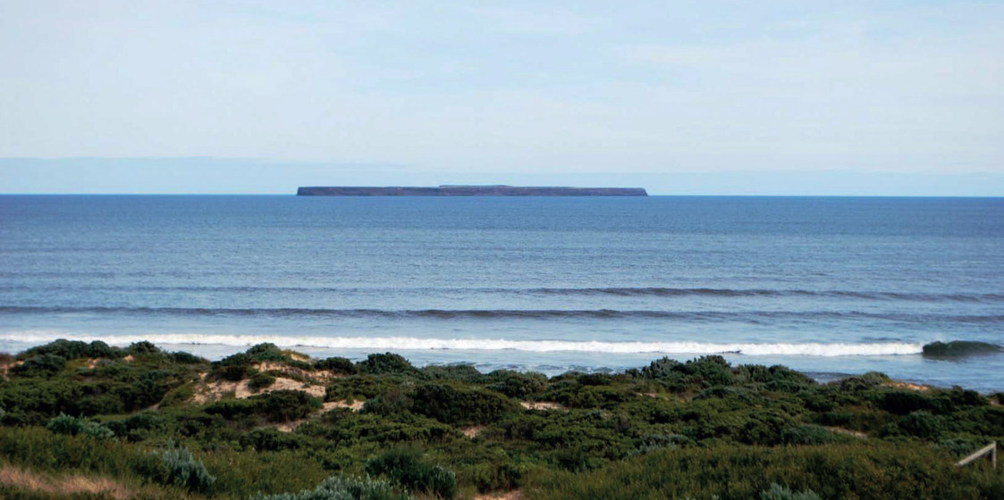 an island appears on the horizon out to sea