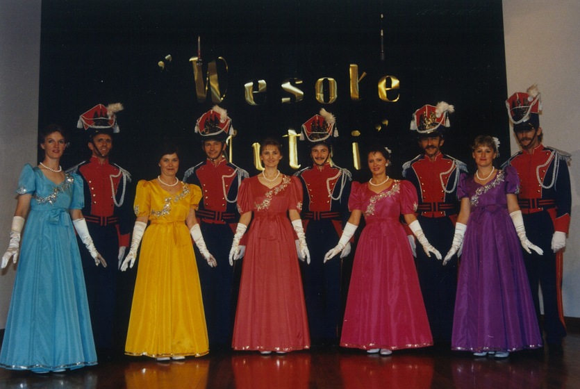 Five couples stand together in colourful traditional Polish costumes