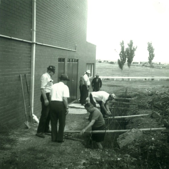 A group of men undertake construction work beside a building