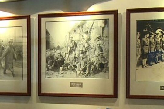 Series of framed black and white photographs on a wall with a propeller mounted above.