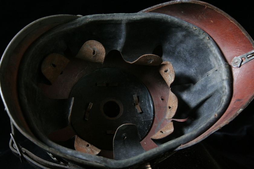 Inside of black helmet showing red and brown leather straps and details.